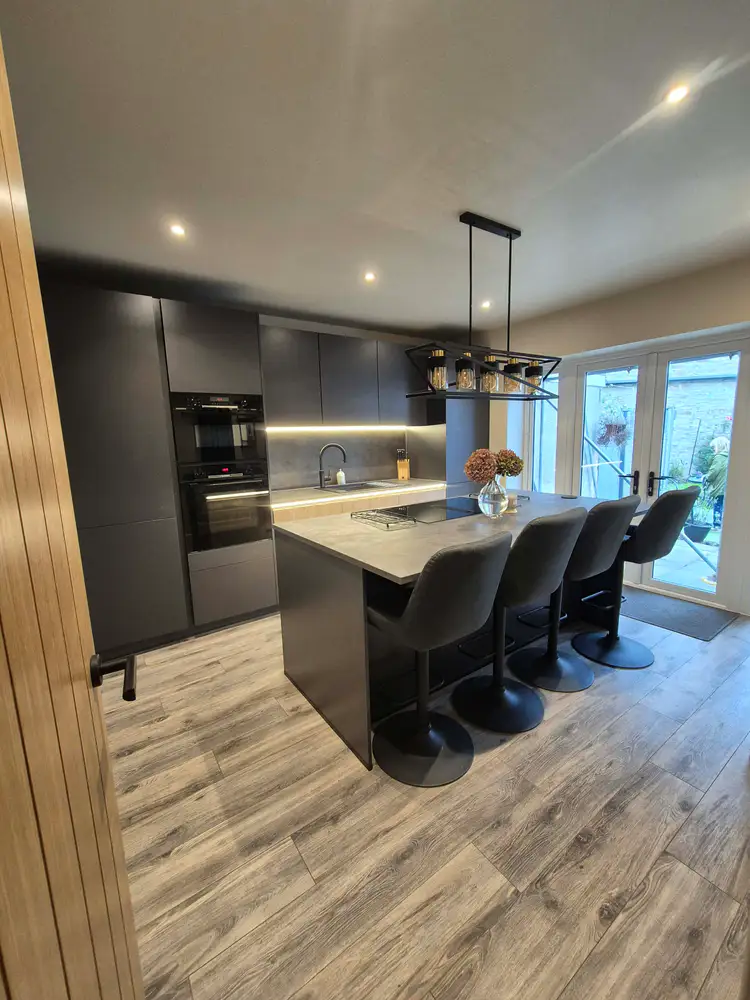 Dark grey kitchen cabinetry and a large island with bar stools