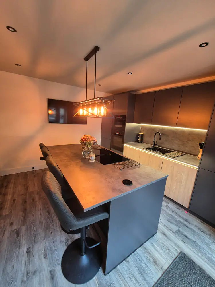 Client-supplied photograph of a completed kitchen with an island and warm pendant lighting